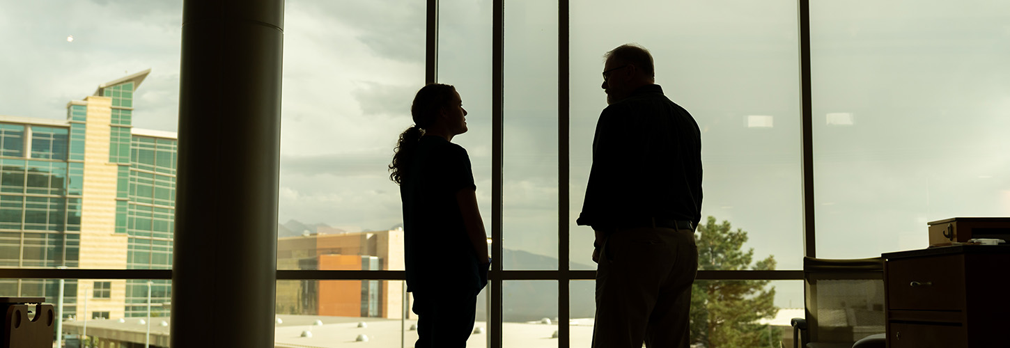 A nurse and a patient stand in front of a window