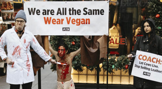 protesters holding anti leather signs with a person tied up and covered in blood