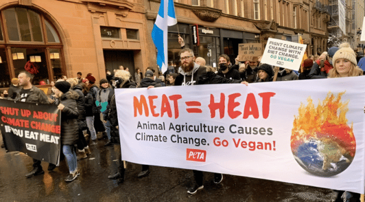people marching with PETA protest sign that says meat equals heat