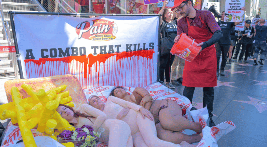 three activists lying in front of a sign that reads a combo that kills