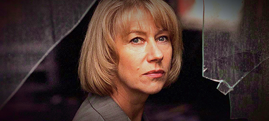 The main character, played by Helen Mirren, gazes thoughtfully in the direction of the camera through a broken-glass window.