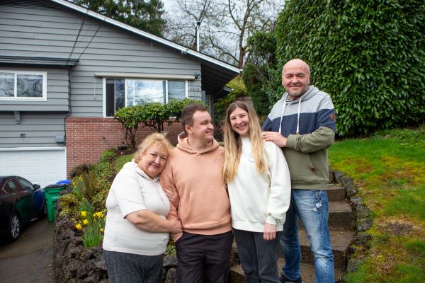Four people stand in front of a house.
