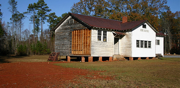 white wooden house with siding being restored