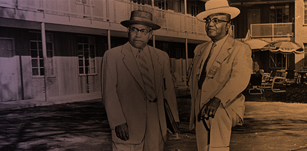 Two gentlemen standing in front of a motel building