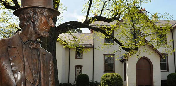Bronze statue of Lincoln in front of a white house