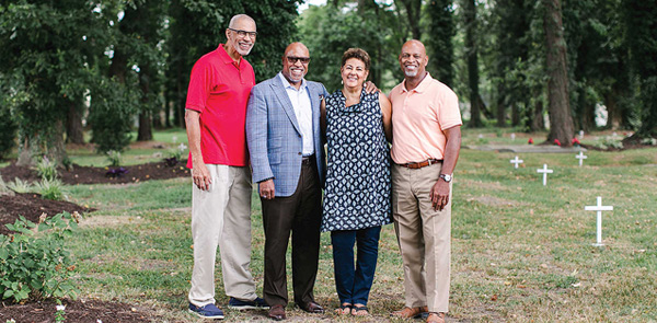 Four people standing together in a cemetery smiling