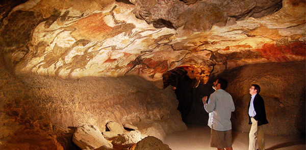 two men looking at cave paintings