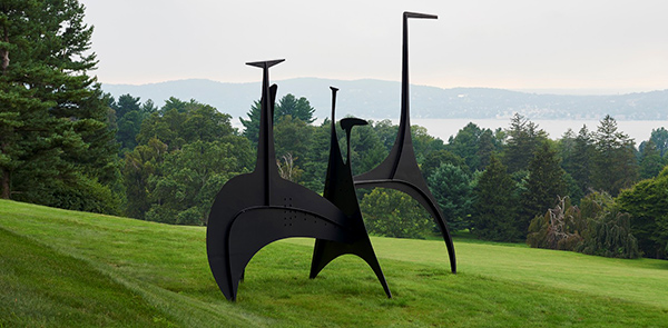Calder sculpture on grassy hill overlooking a river and tres