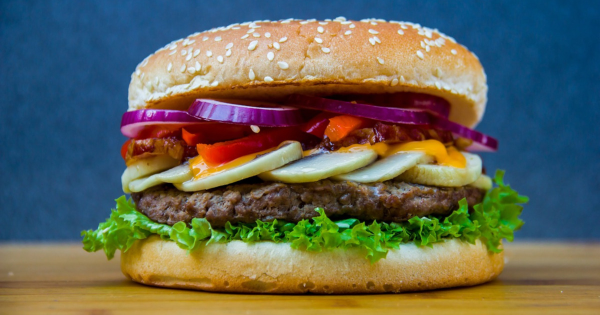 hamburger with vegetables on a wooden cutting board