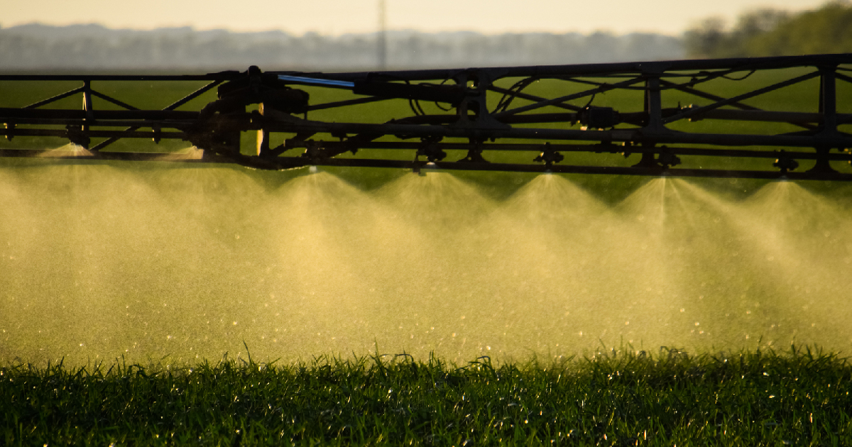 tractor arm on a farm spraying liquid fertilizer on a crop field
