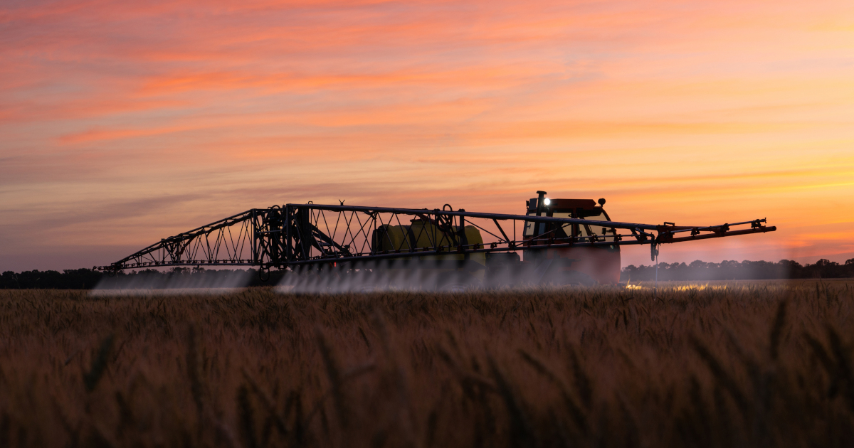 tractor on a farm field spraying herbicides on a wheat crop