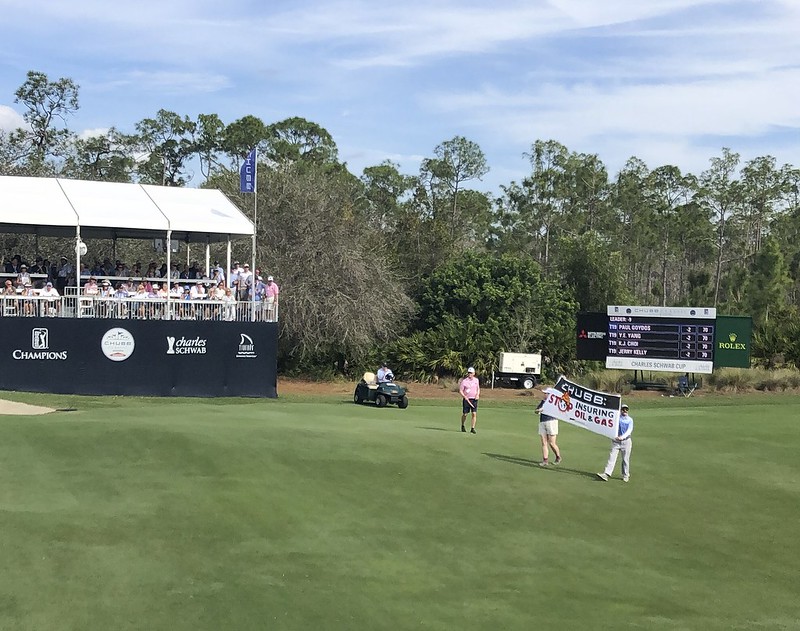 Protestors holding a sign that says Chubb: Stop Insuring Oil and Gas on the green at the Chubb Classic Golf Tournament