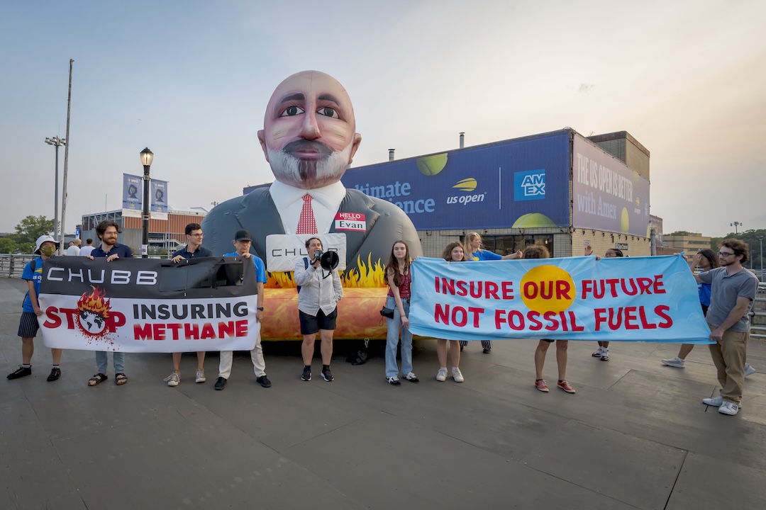 An inflatable of Chubb CEO Evan Greenberg with a banners that read Stop Insuring Methane and Insure Our Future Not Fossil Fuels.