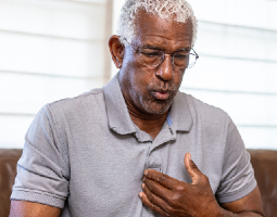 Man holding his chest while experiencing an irregular heartbeat.
