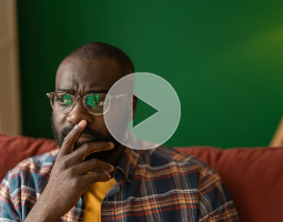 Man sitting on a couch with a concerned expression, reflecting on his health and screening decisions.