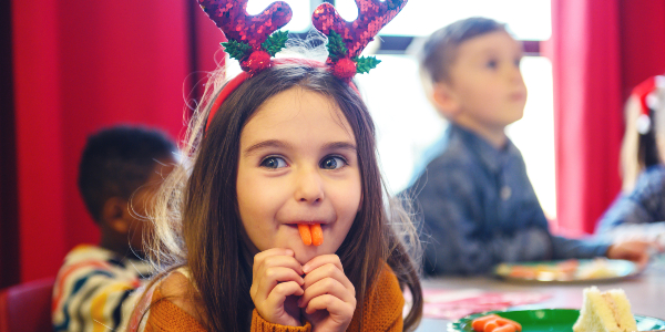 Young girl wearing reindeer antlers and eating carrots