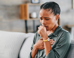 A woman experiencing coughing, a potential sign of an immune disorder.