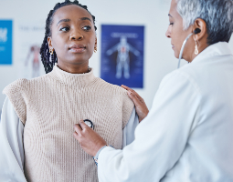 Doctor using a stethoscope to check a patient’s lungs during a health exam.