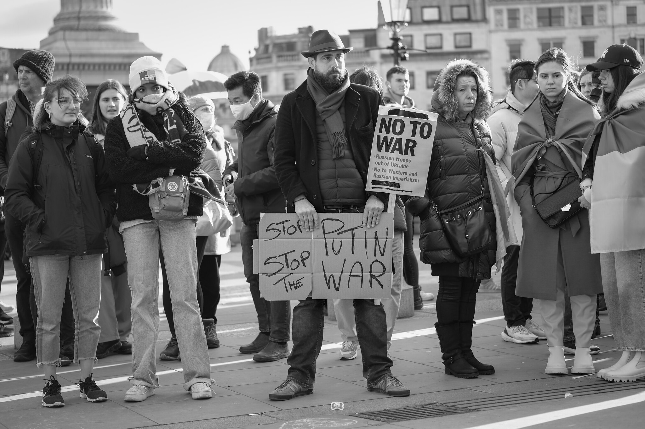 protestors with signs saying stop putin, stop war