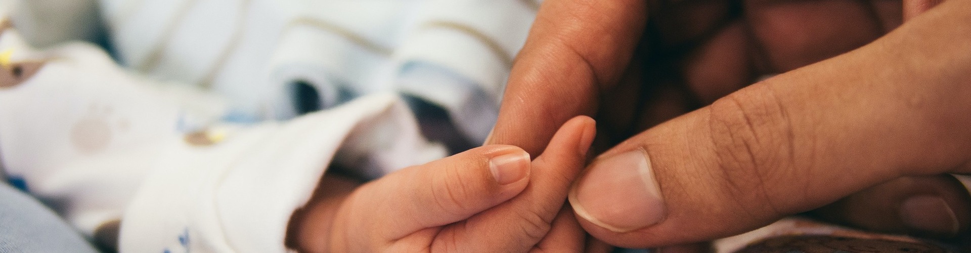 Photo of person holding the hand of an infant