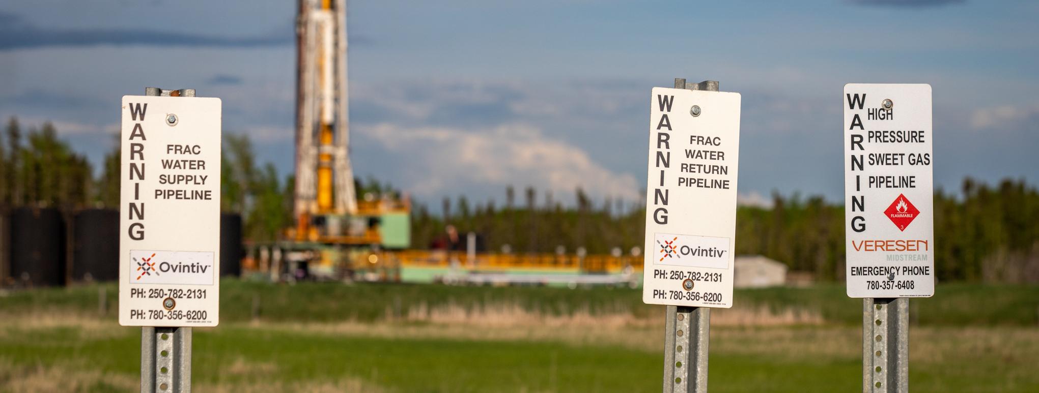 Fracked gas pipeline signs with plant in background