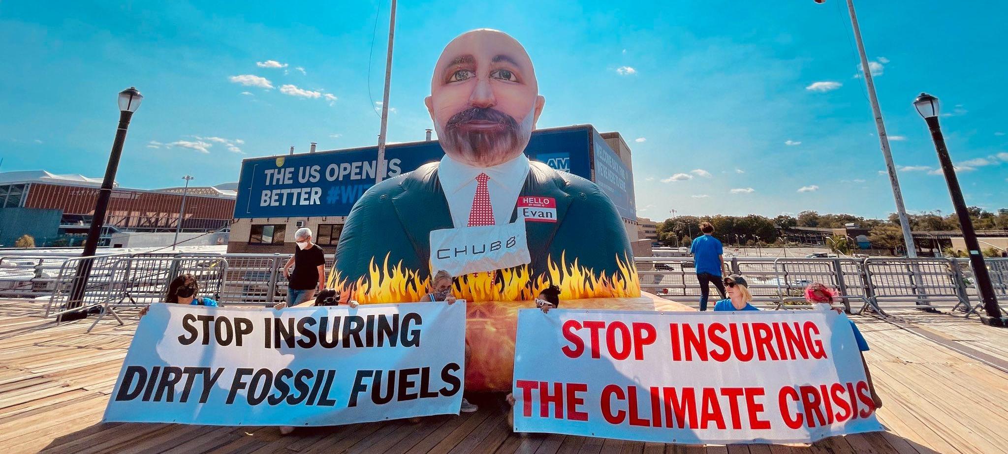 Blow up caricature of Chubb CEO Evan Greenberg with activist signs saying stop insuring climate chaos in front of the US Open
