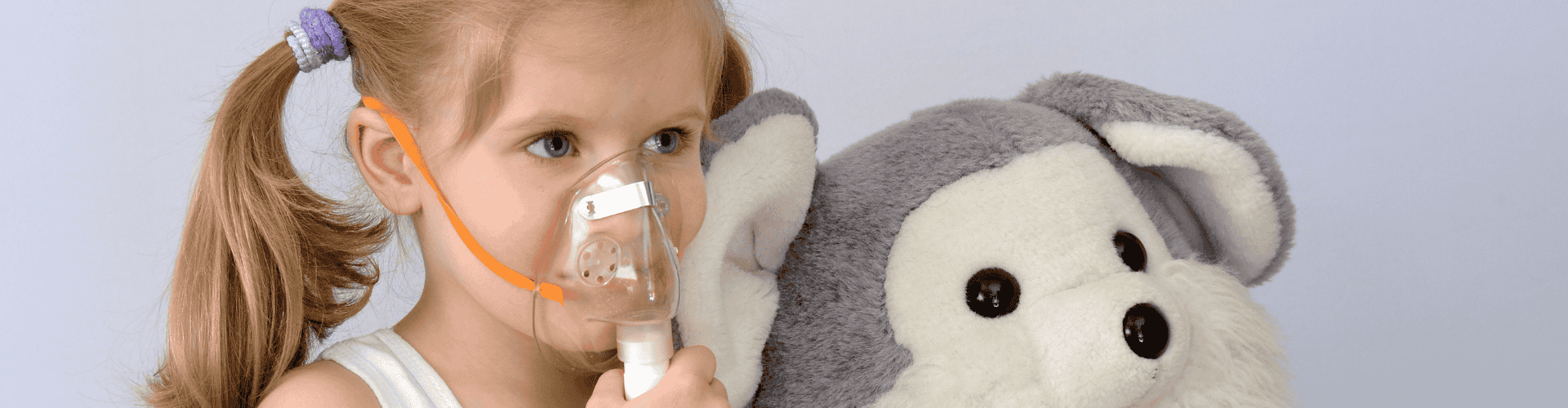 a girl with an oxygen mask next to a stuffed animal