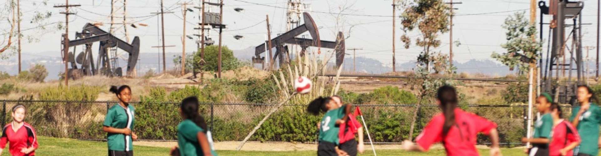 Kids playing soccer next to oil rigs