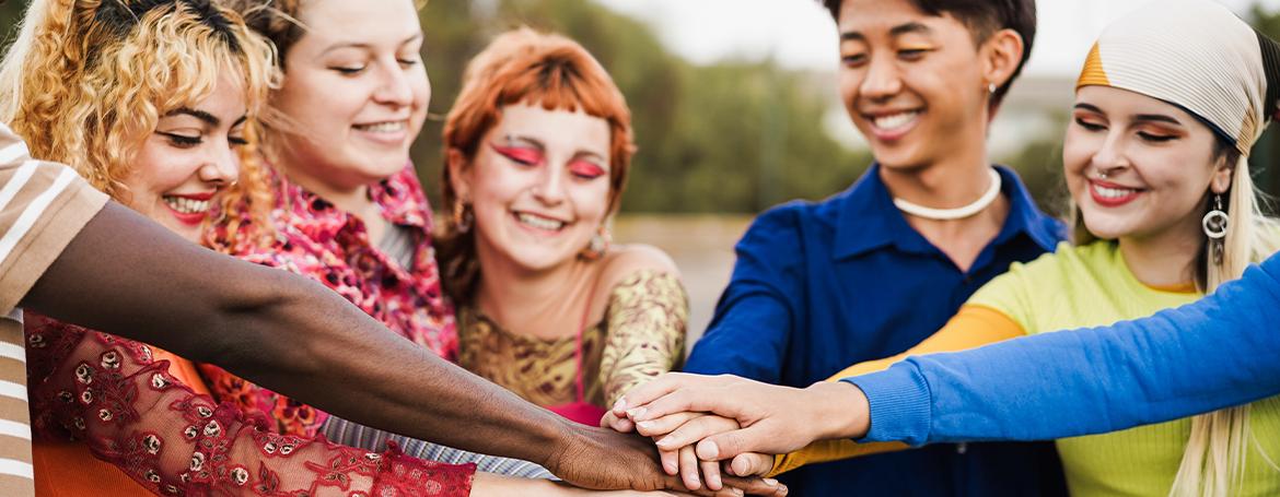 Young diverse people celebrating together stacking hands
