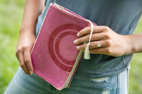 A person holding a pink Bible