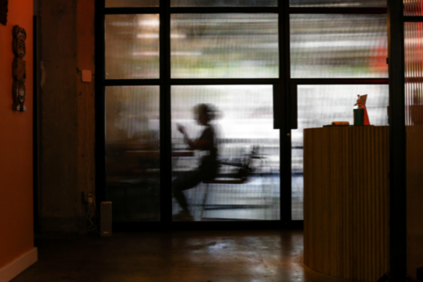 Someone sits at a desk behind an opaque window
