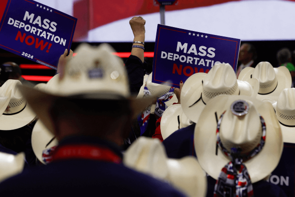 Cowboy hat wearing-crowd holding red, white, and blue signs that say 