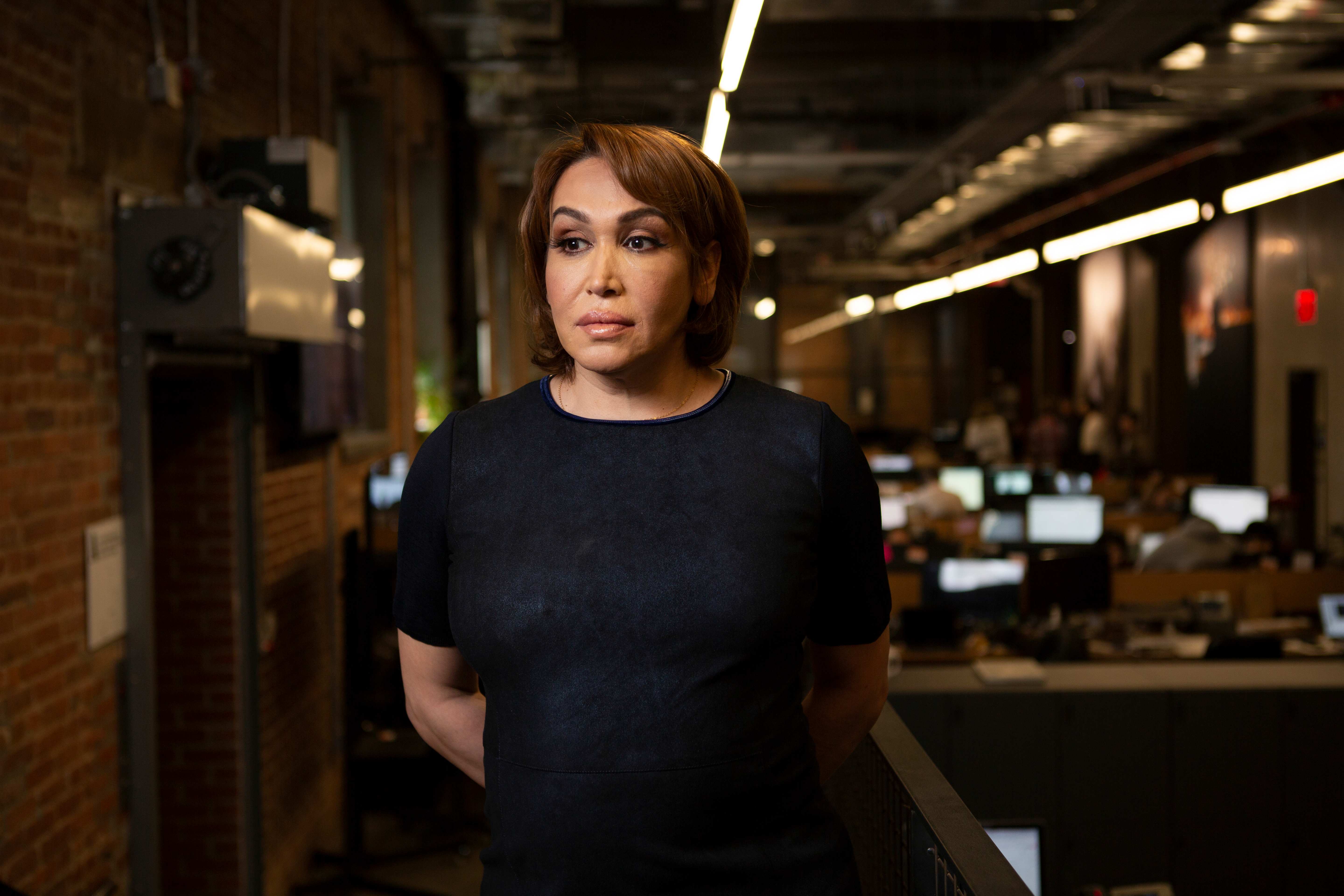 A transgender woman in business attire in an office looking to the side