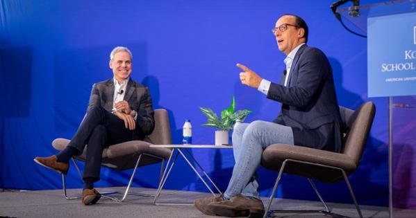 Brett Schulman, seated and speaking Kogod dean David Marchick in front of a blue background.