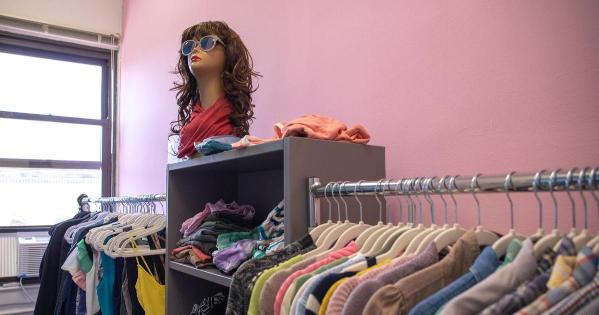 Image of Trans and Queer Cooperative space. Pink wall with a rack of clothes and a mannequin with wig.