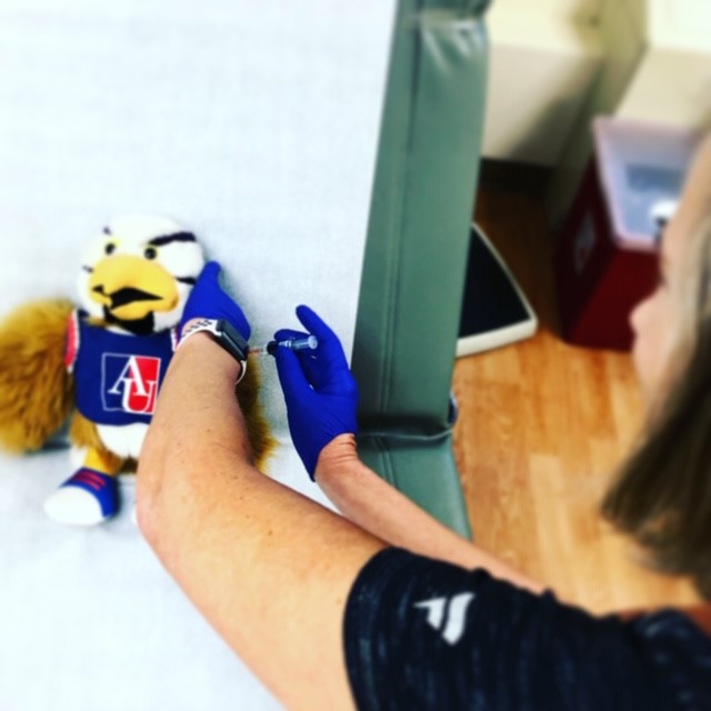 An eagle plush getting a shot from the nurse.