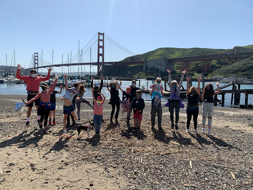 photo of kids enjoying time at a beach near the Golden Gate bridge, cleanup in progress