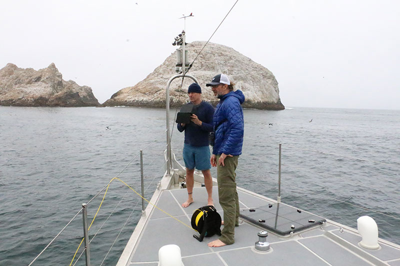 photo of people on a sailboat near some offshore islands