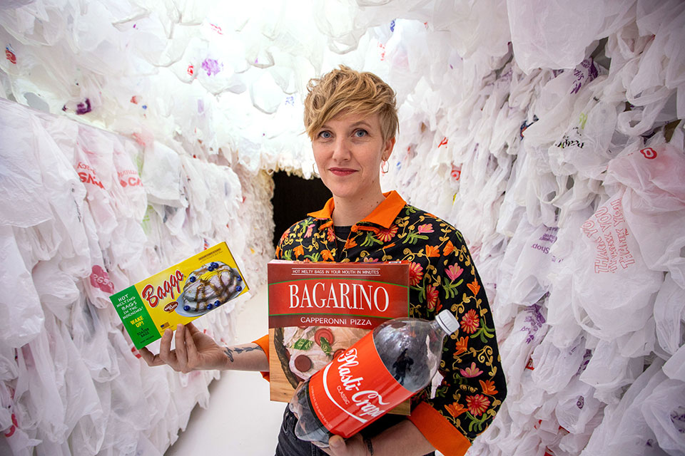 photo of a woman in a plastic canyon, holding mocked-up plastic food products