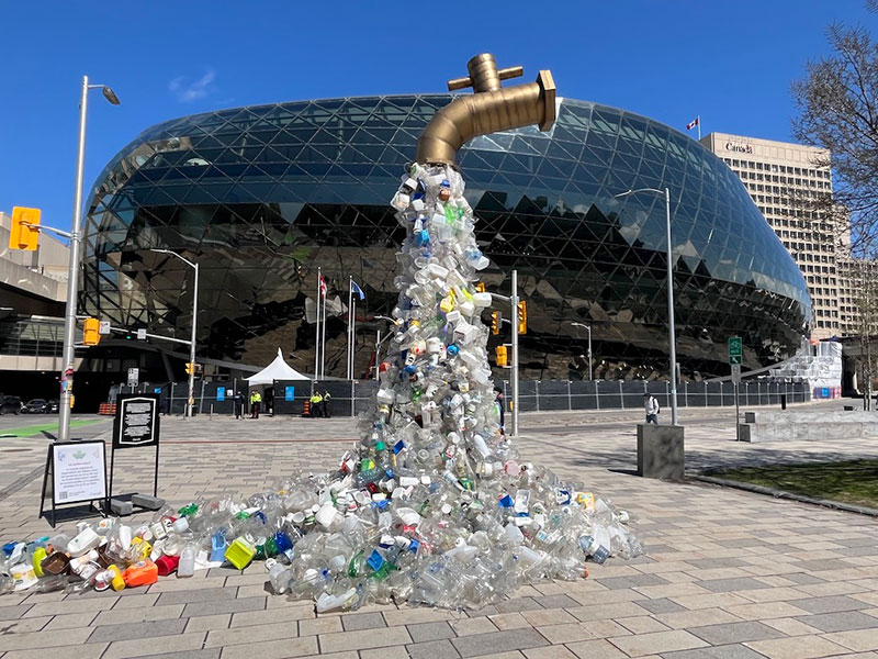 a sculpture of plastic trash flowing from a faucet