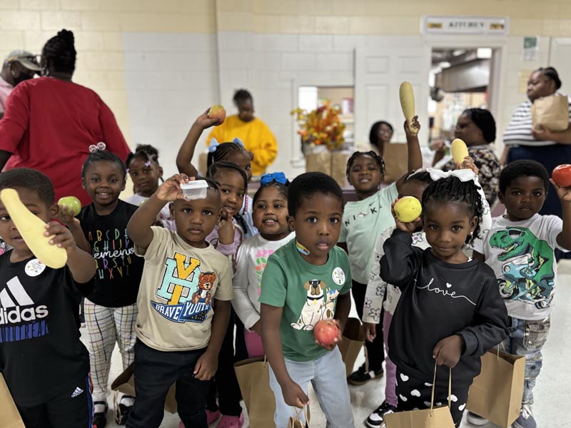 children in a classroom brandishing vegetables