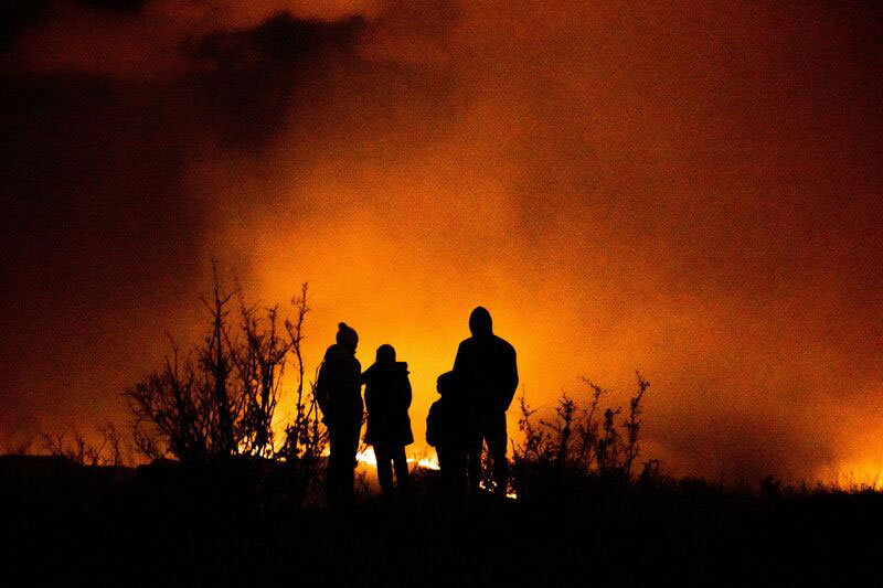 people silhouetted by fire