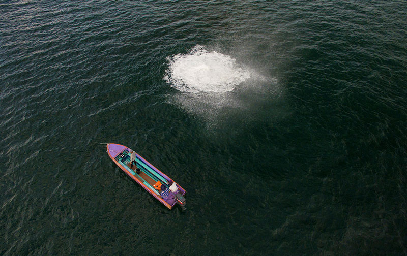 photo of a boat at sea, explosion in the water nearby