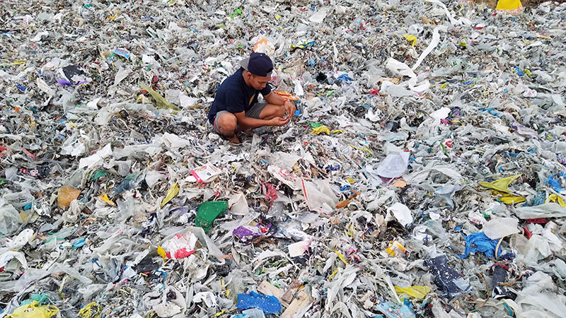 photo of someone sorting through a mountain of plastic discards