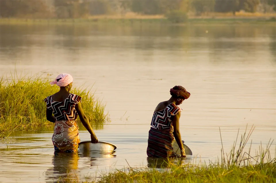 women with pails in a river