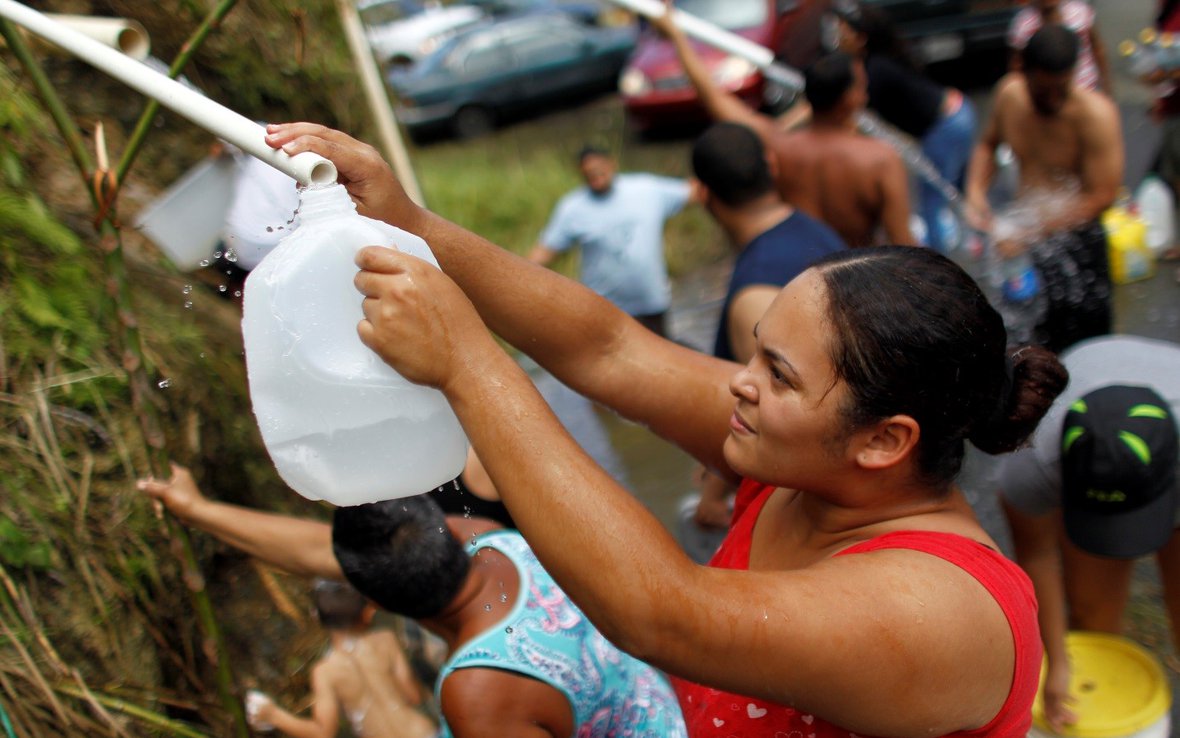 woman collecting rain water after hurricane maria corozal, puerto rico