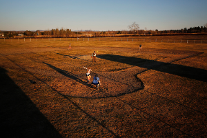 A teacher plays softball with a group of students, May 2019.