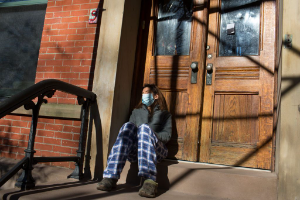 A COVID-19 patient, trying to recover at home, grabs fresh air on the front stoop of her home in Brooklyn, New York, on November 20, 2020.