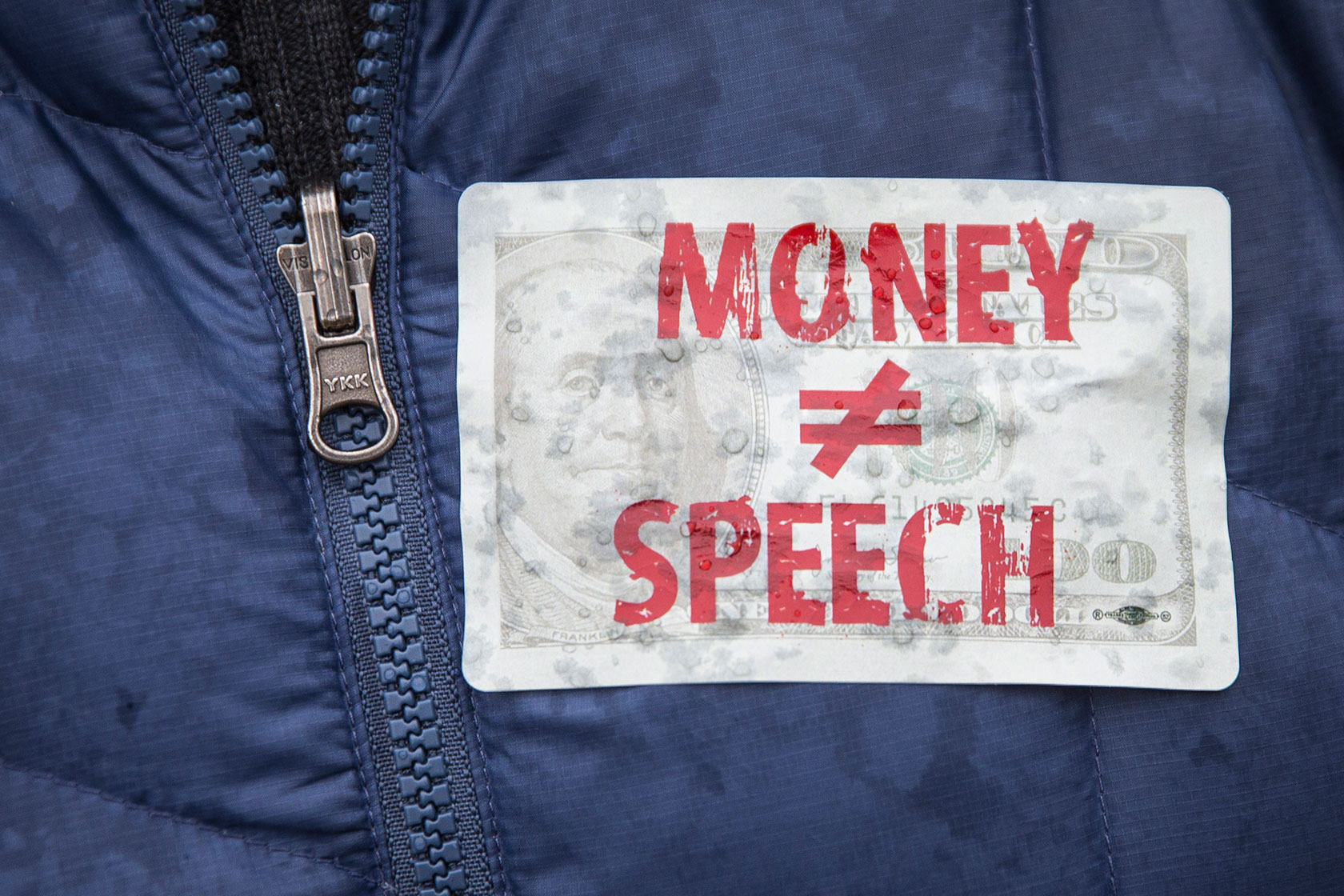 An attendee wears a sticker against money in politics during a rally to mark the fifth anniversary of the Supreme Court's <i>Citizens United</i> decision, at Lafayette Square near the White House, January 2015, in Washington. (Getty/Drew Angerer)