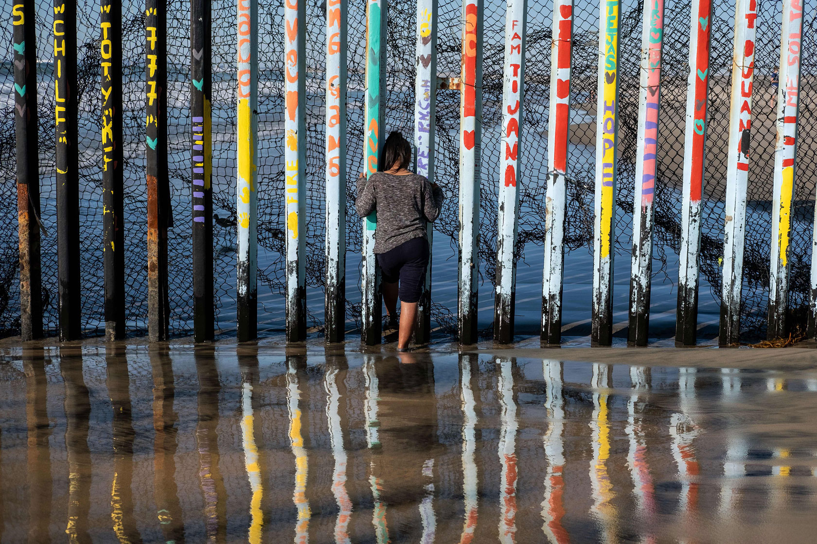 A girl from Salvador, part of the Central American migrants hoping to reach the United States, looks through the US-Mexico border fence in Playas de Tijuana, Baja California State, Mexico.